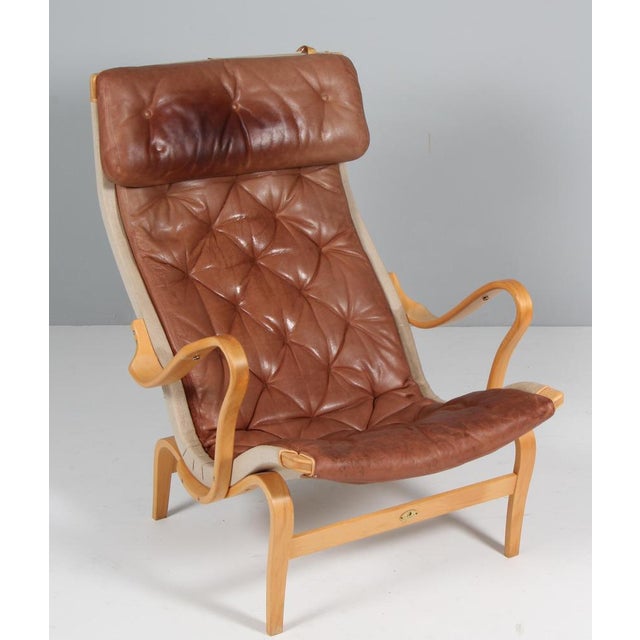 Bruno Mathsson Pernilla lounge chair with patinated leather. Frame in beech. Made by DUX. 25 years annivesary model This...