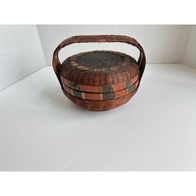 Handcrafted Chinese sewing basket from woven bamboo, reed, or rattan, with red and green accents. Historically used to...
