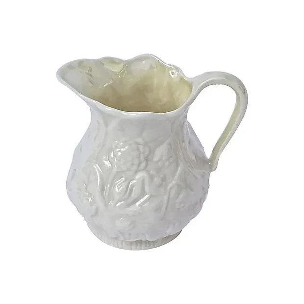 Antique; 1900-1910, porcelain Bleeker floral creamer with handle. Depicts floral designs in bas relief style around...