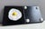 Mixed-media wall panel with foam clay fried egg motif on black lacquered wood domino panel combining playful humor...