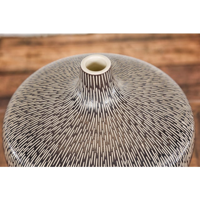 An artisan handmade brown glazed ceramic vase with textured cream strokes. This artisan handmade brown glazed ceramic...