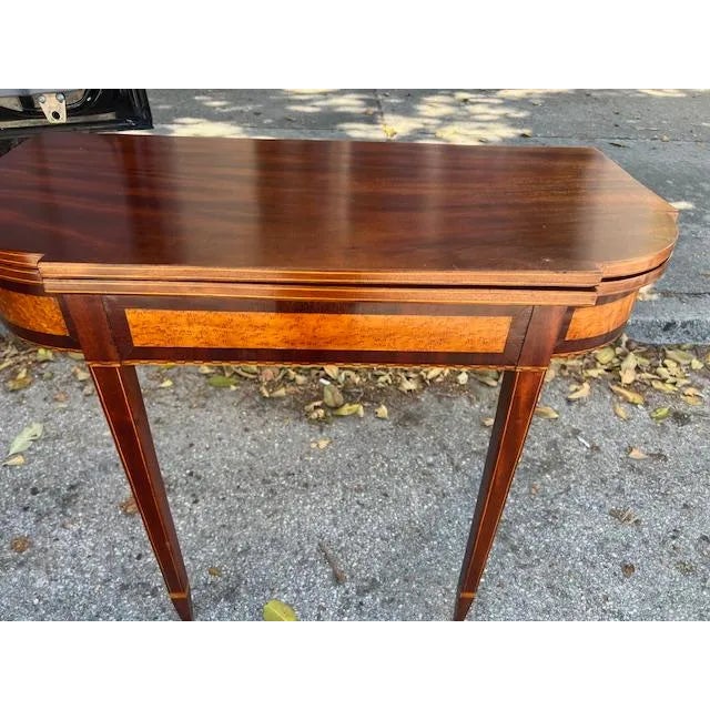 This antique Federal style game table is made of mahogany with satinwood inlay, showcasing intricate craftsmanship and a...