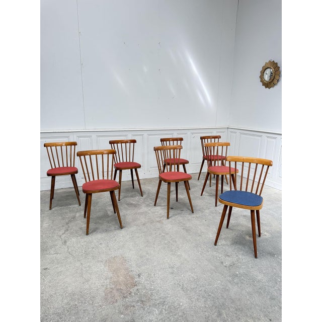 Set of eight vintage Baumann chairs dating from the 1960s with faux leather seats (seven red and one blue). We love their...
