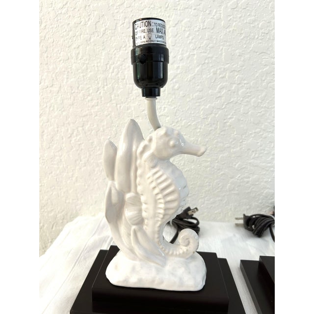 Lovely pair of coastal design table lamps featuring a dark wood two step base with a mounted white figural seahorse. Uses...