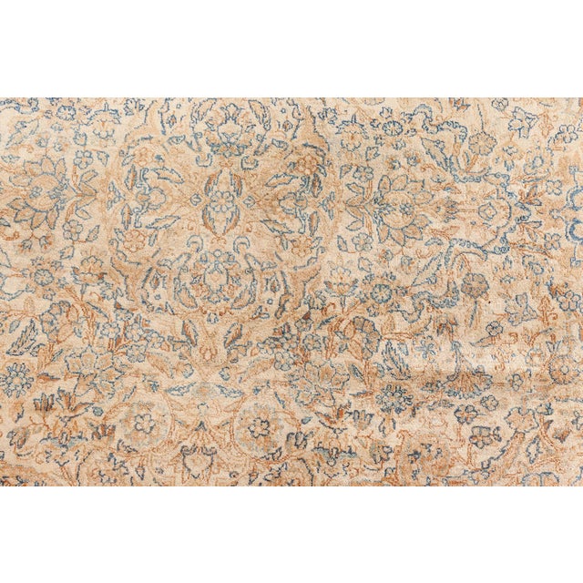 A late 19th century Persian kirman rug, the cream field with a dense overall design of leafy flowering vines and...