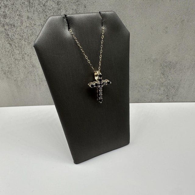 This striking black diamond cross necklace in 14kt yellow gold features 0.86 carats total weight of round black diamonds,...