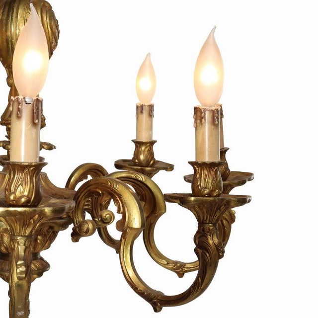 An antique French Louis XIV style 8-light chandelier, crafted from gilt bronze around 1900. This lighting fixture embodies...