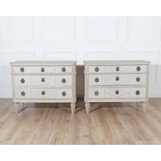 A charming pair of Swedish Gustavian-style painted chests of drawers, dating to the early 20th century, inspired by the...