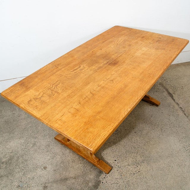 A Scandinavian oak trestle dining table Attributed to Henning Kjaernulf, circa 1970s. This substantial table showcases a...