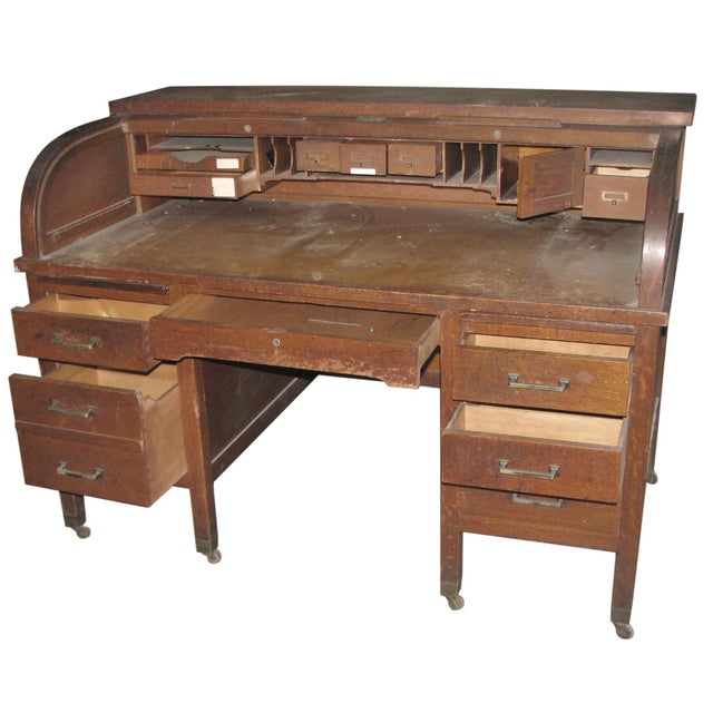 Early 20th century office desk made of quarter sawn oak. A tambour roll top door covers the work area. Six large drawers...