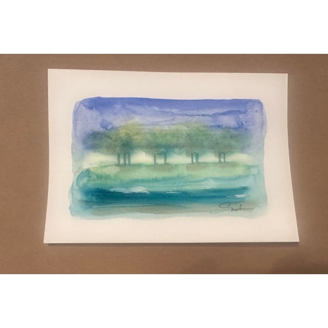 An original watercolor painting capturing the quiet beauty of a misty lakeside landscape. Soft washes of blue, aqua, and...