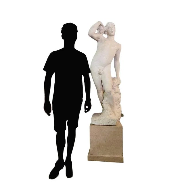 Large stone sculpture depicting a standing, naked man surrounded by grapes and vine leaves - an allegory of autumn....