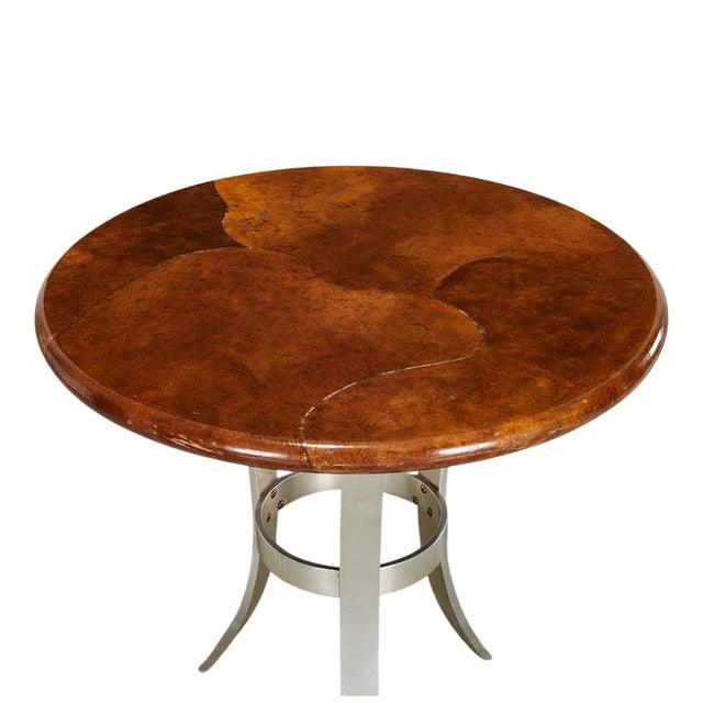 A round side table crafted with a tortoise colored goatskin top and an aluminum tripod base with splayed legs. The mid...