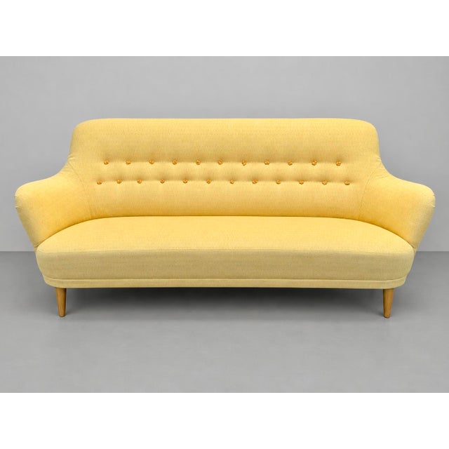 The sofa, in good condition, was reupholstered in yellow cotton fabric, replacing the original. This piece is attributed...