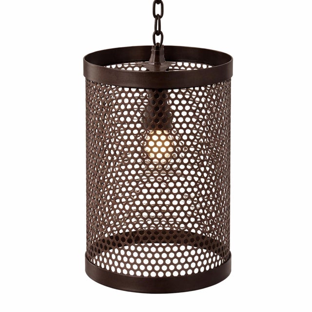 Perforated iron pendant light featuring a cylindrical drum form with evenly spaced circular cutouts that create a subtle...