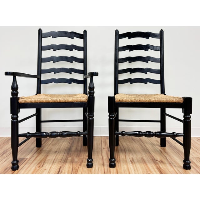 Vintage set of six rich black ladderback chairs with firm rush seats. Set consists of two chairs with arms (measure 23" W...