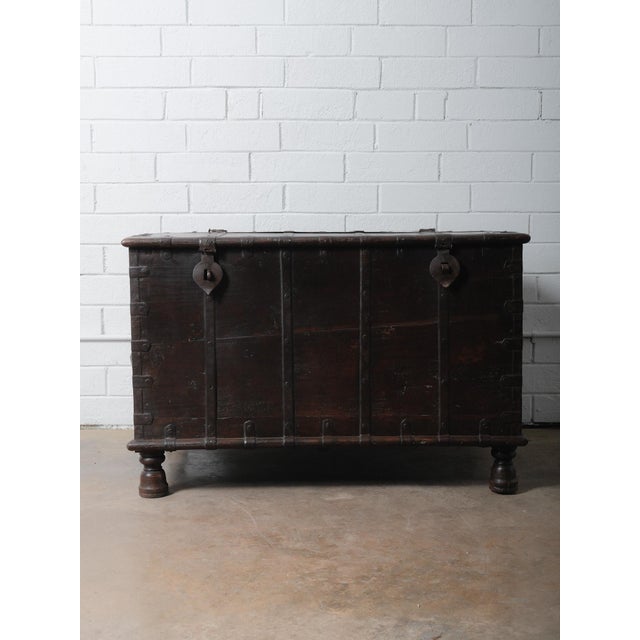This vintage wooden storage chest from India features impressive iron-bound construction, forged metal strapping, and...