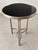 Elegant round accent table featuring a polished black marble top set waiting a silver-tone metal frame. the sculptural...
