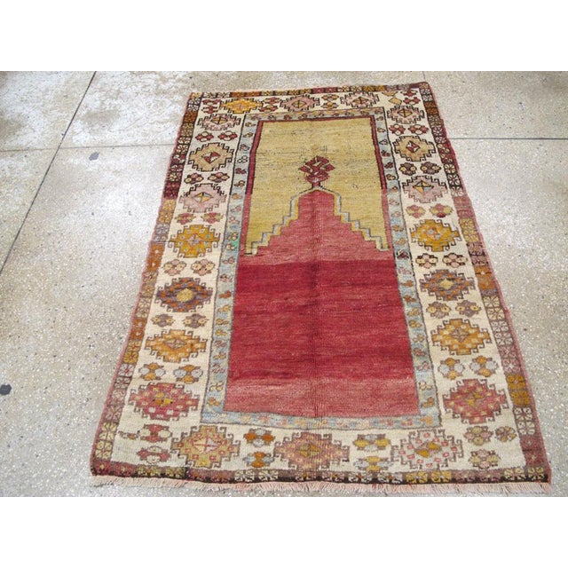 This early 20th century Turkish Anatolian rug, measuring 3' 5" x 4' 10", showcases the traditional prayer niche design...