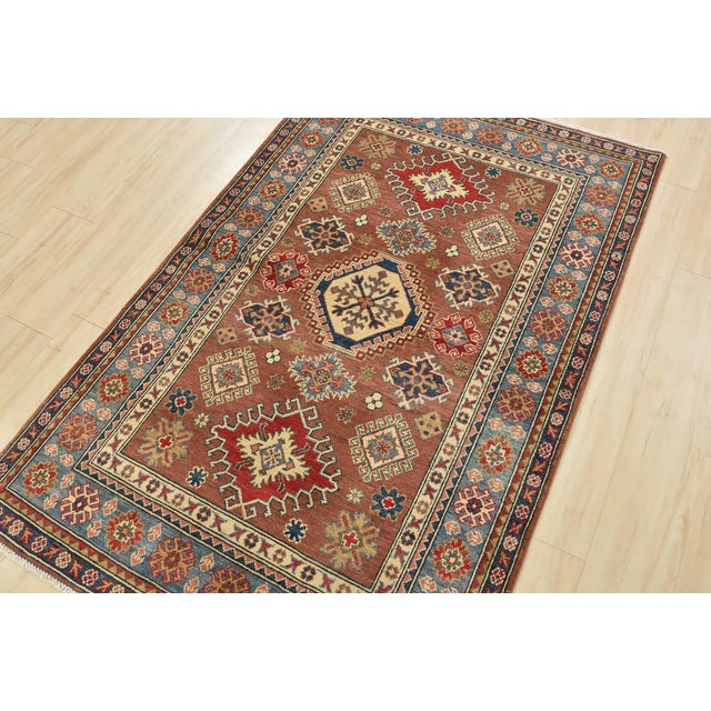 A tribal Caucasian Kazak rug hand-knotted with an all-wool pile on a cotton foundation. This oriental rug features...