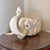 This is a striking ceramic planter in the shape of an elephant’s head, finished in a creamy off-white glaze. The elephant...