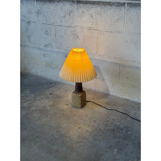 A textured square base tapers into a slender neck to give this table lamp an organic aesthetic. Paired with a classic...