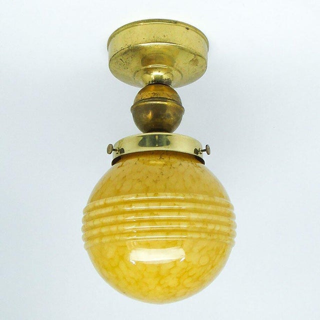 It is made in the art deco style. The structure is made of brass and the lampshade is made of glass. It is preserved in...