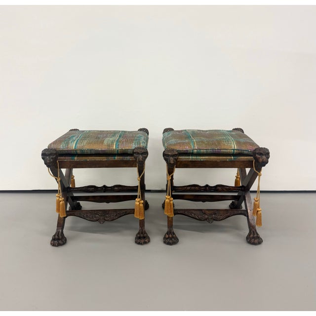 A theatrical pair of vintage curule-form stools crafted from dark-stained carved wood. Each features sculptural lion-head...