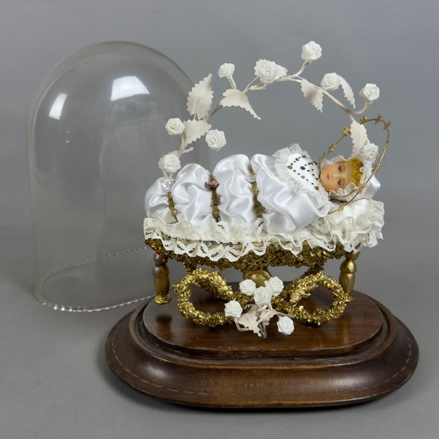 A rare and evocative devotional composition depicting the swaddled Baby Mary lying in a gilded cradle under a bell with a...