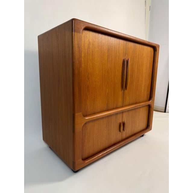 A stunning mid-century modern highboard/TV cabinet from Dyrlund, crafted from elegant teak. The sideboard features...