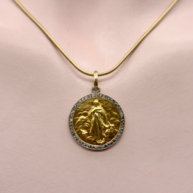 Circa 1912, this French 18k gold pendant features an image of Saint Mary surrounded by diamonds set in platinum. The image...