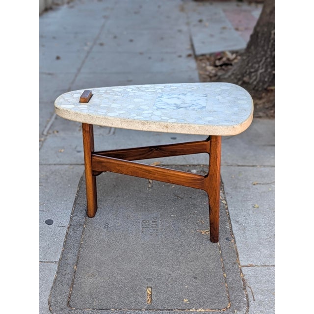 A vintage occasional table in the style of Harvey Probber, estimated mid-20th century. The biomorphic terrazzo top, inset...