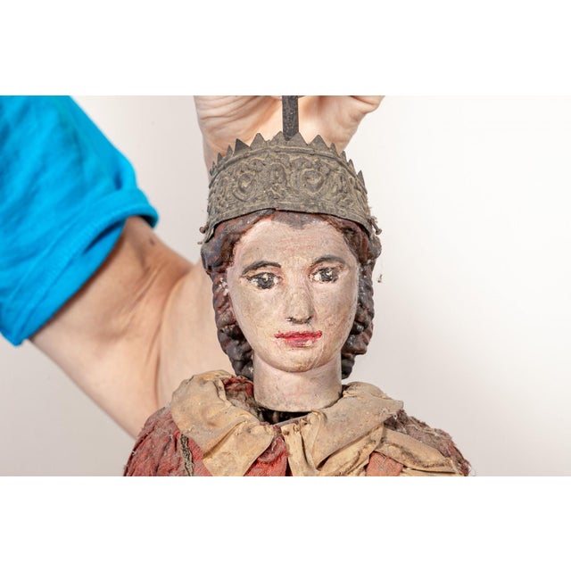 A large wooden marionette of a crowned princess figure, painted with a fair complexion and dark hair beneath a tarnished...