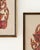 A decorative pair of framed Thai/Southeast Asian rubbing-style wall art pieces featuring classical figure imagery in rich...
