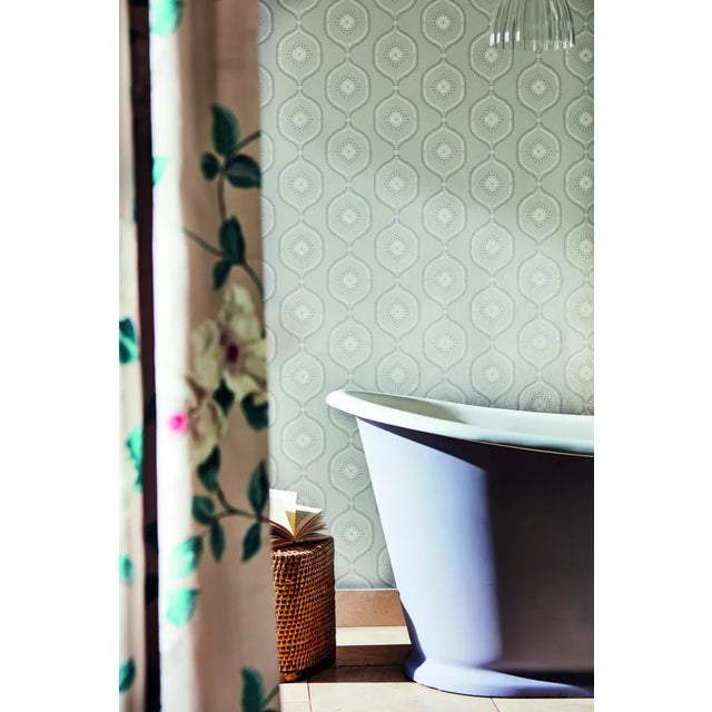 With a chalky ground and hand block printed look this wallpaper’s stylised ogee trellis houses a delicate flower and...