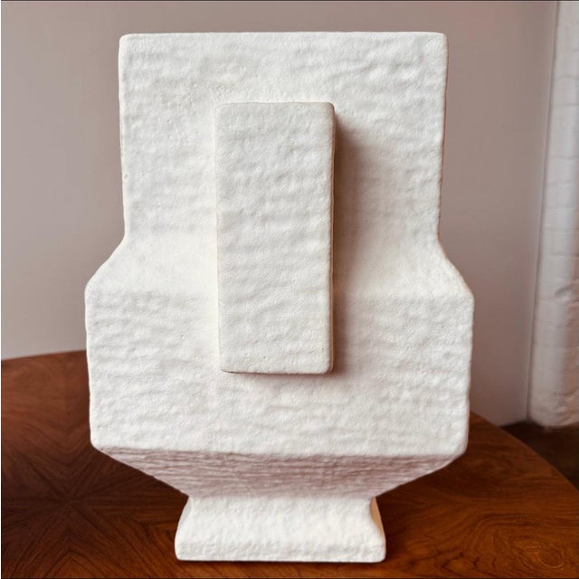 Oversized stoneware vases or urns with a hammered texture and geometric shape with two handles, and matte white finish.