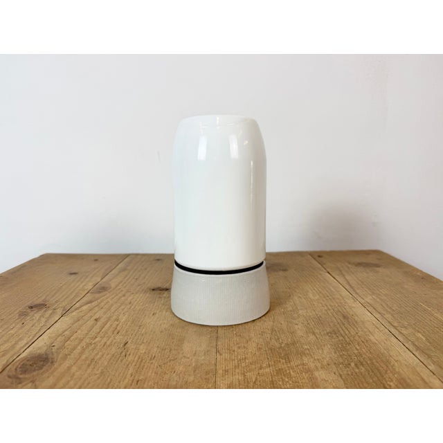Vintage industrial ceiling or wall light made in former Czechoslivakia during the 1970s. It features a white porcelain...