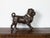 An English terracotta standing dog sculpture from the early 20th century, with glass eyes, green collar and bells. Created...
