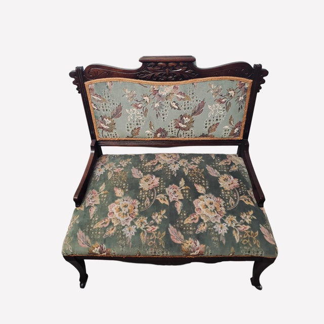 This antique Eastlake-style carved settee features decorative carving along the backrest and lower apron, resting on...