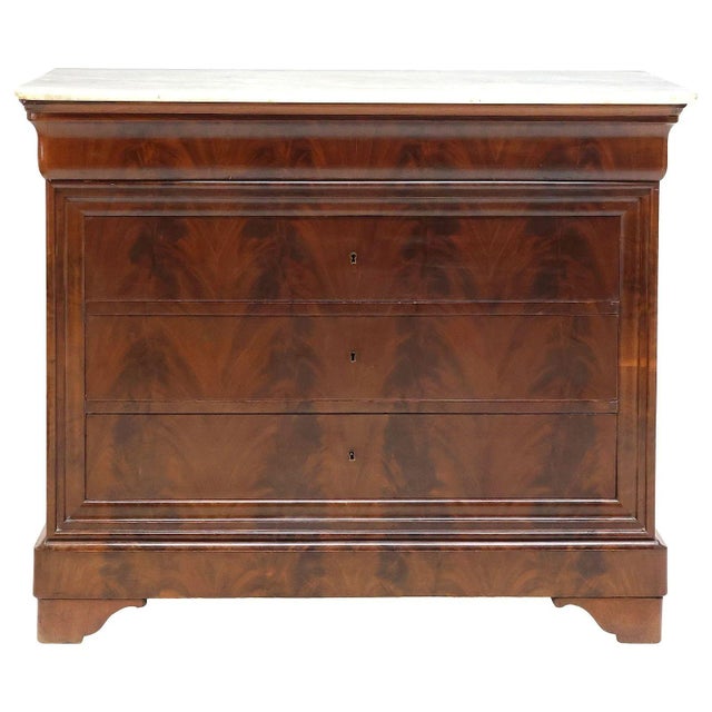 A refined white marble top French Louis Philippe commode, mid 19th-Century, crafted of burled mahogany with beautifully...