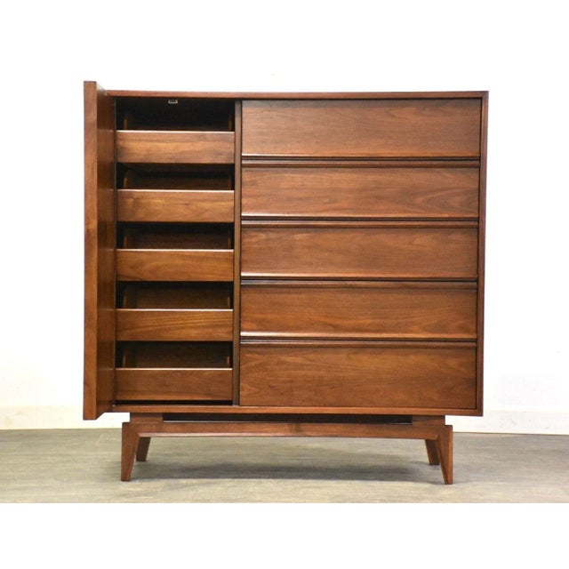 A mid century modern walnut armoire dresser with sculpted legs and a large door concealing additional drawers....