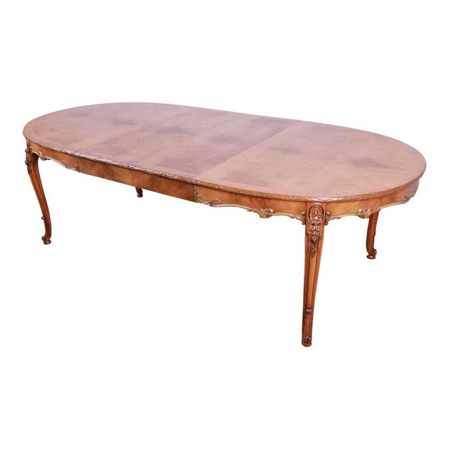 Vintage ornate burl wood French carved dining table by Romweber. The refinished table has a banded edge and expertly book...