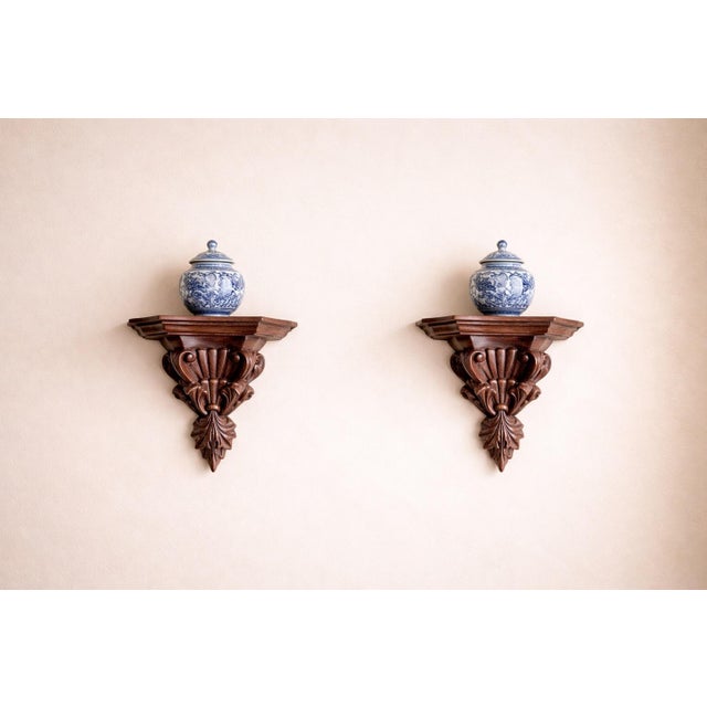 This refined pair of carved wood corbel wall shelves features classic scroll and acanthus leaf detailing, designed as...