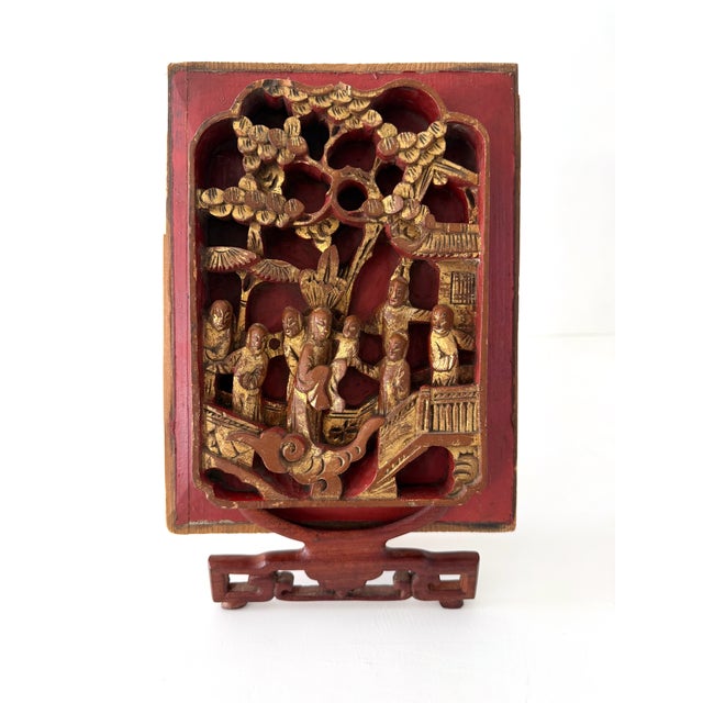 Antique hand carved wood panel on rosewood easel. This beautiful panel is lacquered in red with gilt accented carvings....