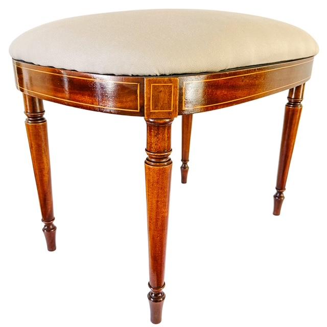 An exquisite Edwardian-era Sheraton Revival oval vanity stool, masterfully crafted from rich mahogany with refined boxwood...