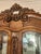 Elegant Italian wood curio cabinet has a rich brown finish with intricate floral and scrollwork carvings on the crown and...
