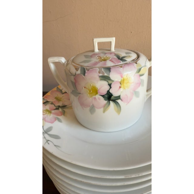 This early 20th century Nippon Azalea porcelain set includes 6 dessert plates, 6 tea cups with saucers, 2 sugar bowls with...