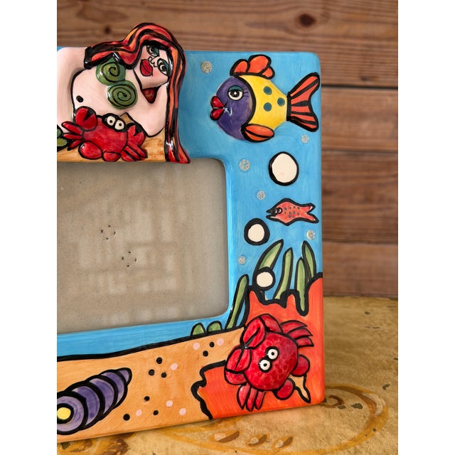 Whimsical hand-painted coastal picture frame featuring a playful mermaid surrounded by tropical fish, crabs, seashells,...