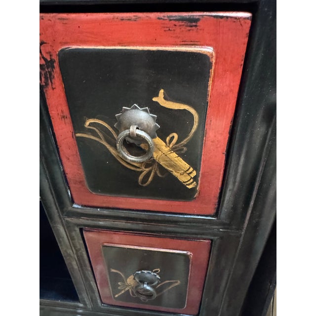 A dramatic vintage Chinoiserie cabinet finished in black painted wood with hand-applied gilt landscape scenes, beautifully...