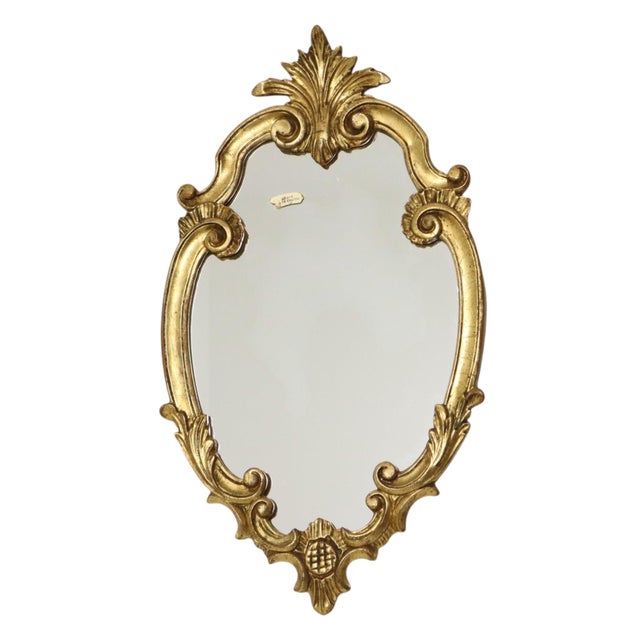 Vintage crest mirror, gold-leaf gilded, France, circa 1960s–70s. The frame is elaborately decorated with graceful, curling...